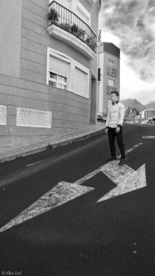 ein Mann steht auf der Straße auf einem Richtungspfeil